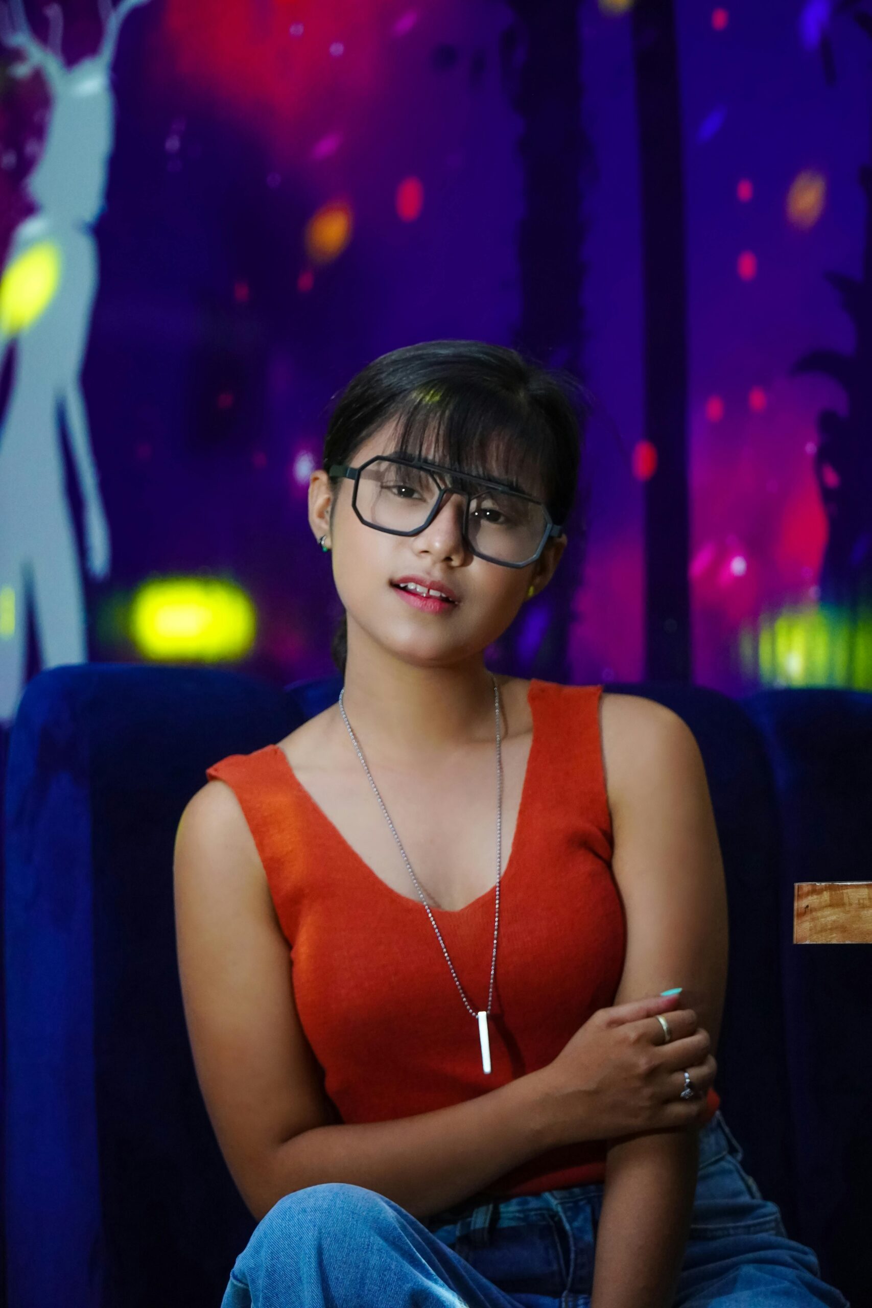 Fashionable young woman in a red top at a vibrant night club, exuding modern style.