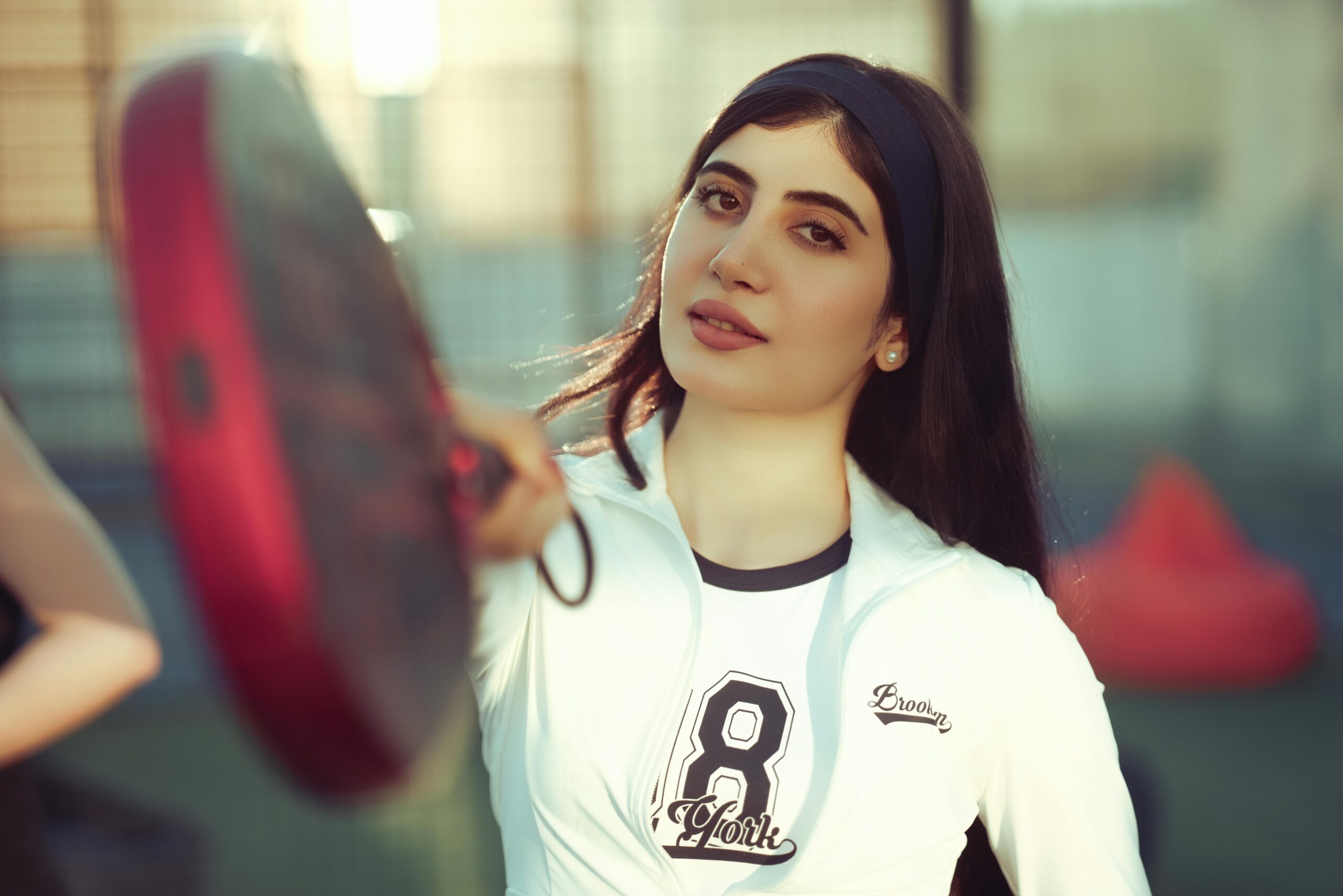 Focused young woman playing padel in an outdoor court in Baghdad, Iraq.